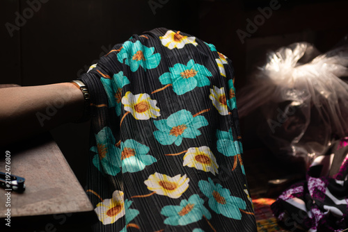 фотографія Pleated black fabric with bright teal and yellow floral patterns draped over a s