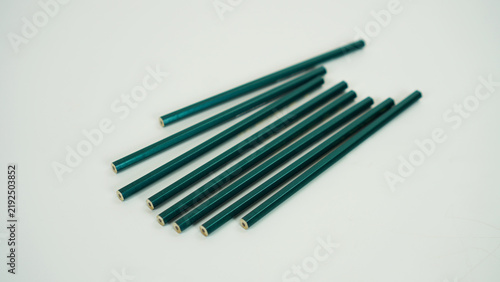 Canvas Print Eight unsharpened bottle-green pencils lying in a haphazard arrangement against a white background