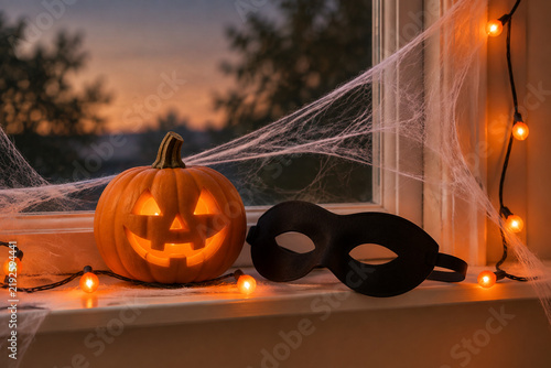 Carved pumpkin and mask with cobweb, Halloween window display concept