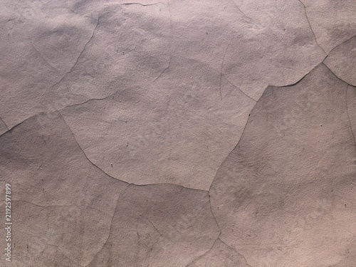 Close up cracked concrete wall texture with pinkish tint, old stucco surface showing fractures and peeling paint background detail