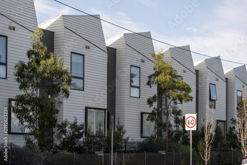 Canvastavla Row of modern architecturally designed townhouses with angular rooflines and cladding facades, Australian native trees, and a 60km/h speed sign, Melbourne, Victoria, Australia
