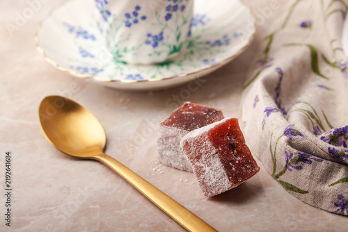 Foto Pink candy sits on soft pastel surface beside gold spoon