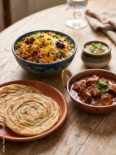 Indian food biryani curry and paratha on wooden table