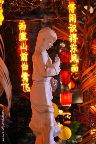 Stone statues of women and LED lights inscribed with poetry. Night view of Yaxiang Street, Liaobu, Dongguan, China.
