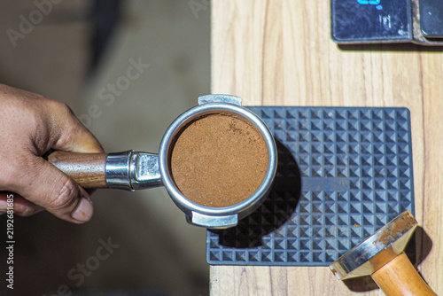 Fotografie Hand holds coffee grounds in portafilter