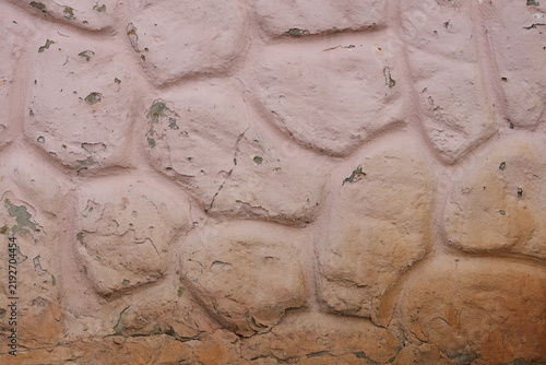 Foto Textured pink wall with aged peeling coating and exposed stonework beneath