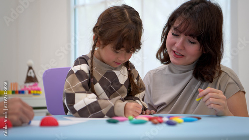 Teacher or parent helping a child color the picture with color pencil, enhancing creativity and fine motor skills development