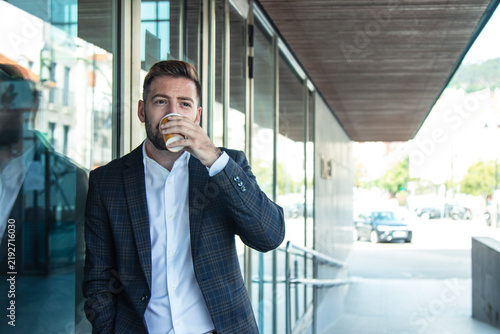 Businessman drinking coffee outside office building
