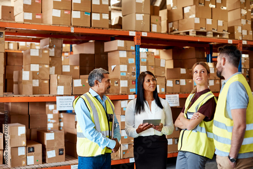 Logistics, manager or team in depot with tablet, stock control or task discussion in meeting. Happy, people or coordinator with tech, inventory management or dispatch instruction at storehouse.