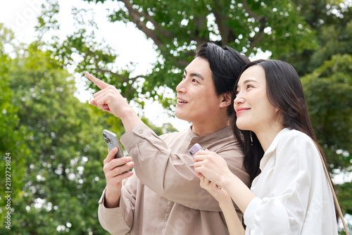 Foto 公園でスマホを持って話す笑顔のカップル30代