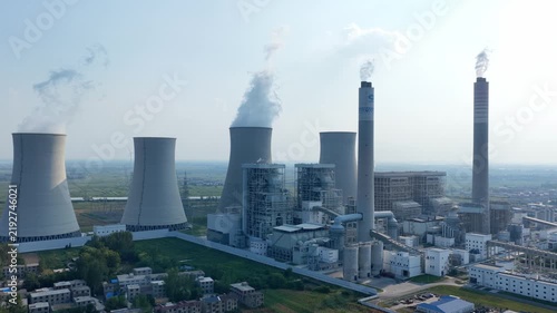 Large thermal power plant cooling towers and smokestacks emitting steam
