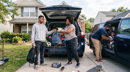 African American family packing car for road trip outside suburban home.