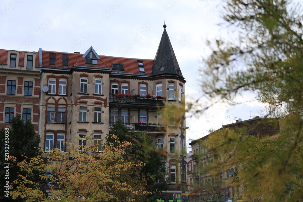 Obraz premium Historic European Residential Building with Tower Surrounded by Autumn Trees