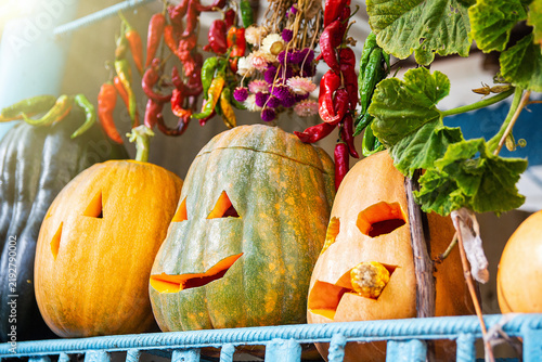 Rustic Homemade Halloween Decoration with Carved Pumpkins and Peppers, red and green chili peppers, dried flowers, and autumn foliage.