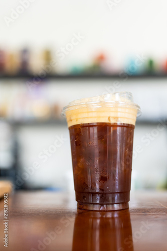 Refreshing iced cold brew in a transparent plastic cup on wood table