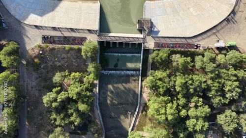 Top-down aerial view of river promenade park and dam infrastructure at early morning