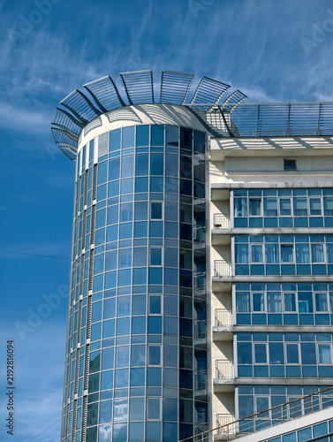 Blue high rise housing building with elegant balconies and multiple glass apartment windows