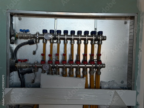Foto Underfloor heating manifold with pipes, valves and gauges installed in a wall re