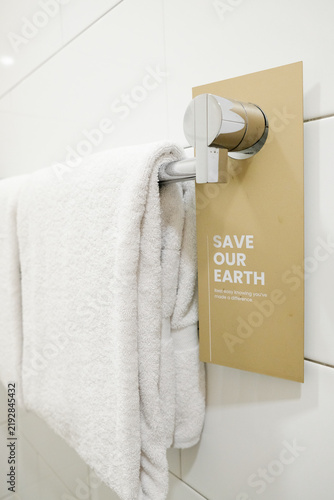 Save our earth eco-friendly sign on a hotel bathroom towel rail