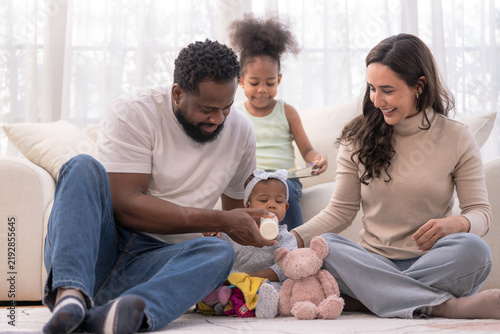 Принти на полотні A happy multiracial family sits on the floor enjoying family playtime during a cozy weekend at home, radiating warmth and connection a bright authentic lifestyle scene