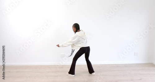 Young girl practicing martial arts moves in bright, minimalist room