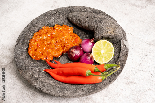 Indonesian red chilli paste on the stone mortar and pestle .