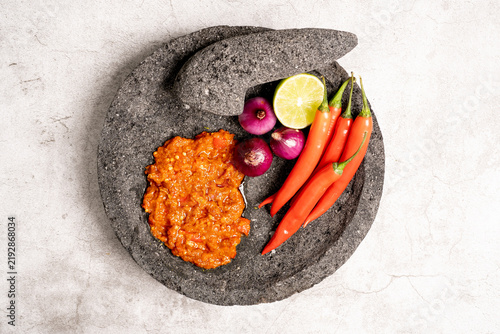 Indonesian red chilli paste on the stone mortar and pestle .