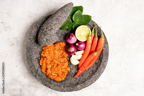 Indonesian red chilli paste on the stone mortar and pestle .