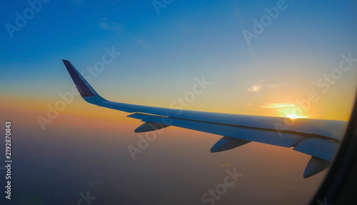 View from airplane window looking out at aircraft wing during a beautiful pastel sunset scene