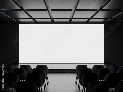 Empty conference stage with white projection screen and rows of chairs