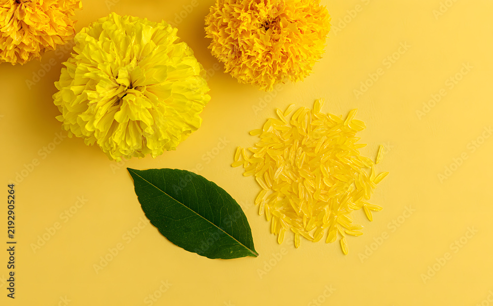 Obraz premium Joyful Dussehra. Yellow blooms, emerald foliage, and a rice pattern on a yellow backdrop. Conceptual representation of the Indian festival.