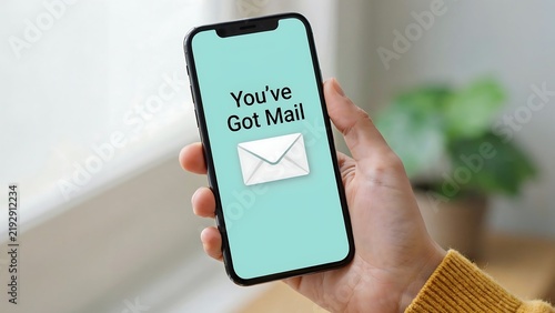 Hand holding smartphone with 'You've Got Mail' notification during bright daylight with copy space
