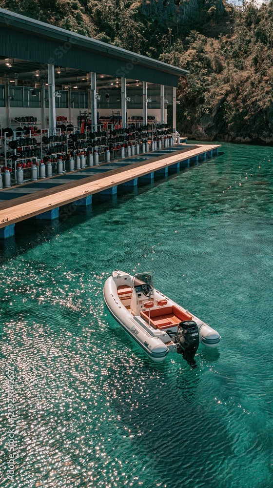 Fototapeta premium Inflatable boat docked at a tropical resort's dive center with scuba gear and clear turquoise water