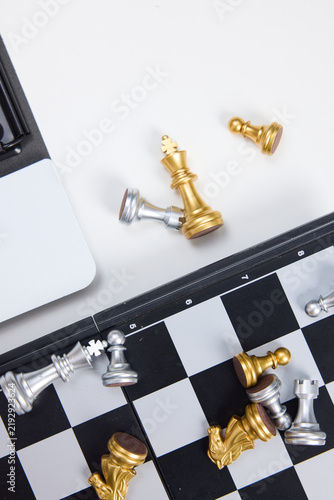 Фотография Chess Pieces on Board with Laptop, Strategy and Competition Concept