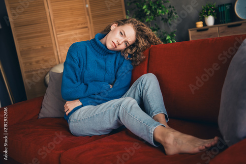 Obraz na plátně Young woman with curly hair in cozy knitted sweater enjoying a peaceful day at h