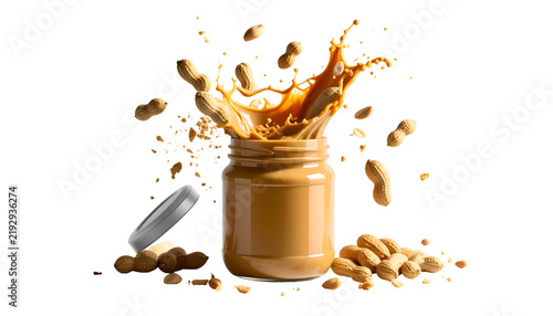 Peanut butter jar open; creamy splash erupts with peanuts around on black background