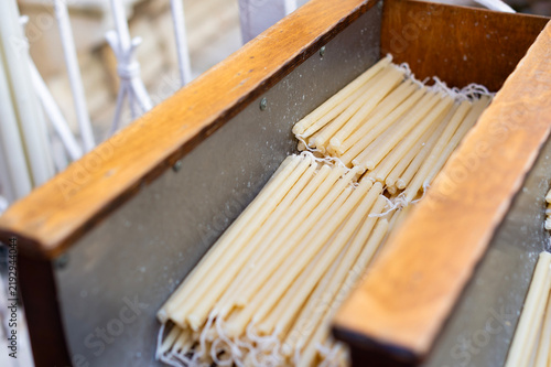 Fotografía Thin yellow beeswax candles rest in a wooden box inside a church in Kerkira, Greece