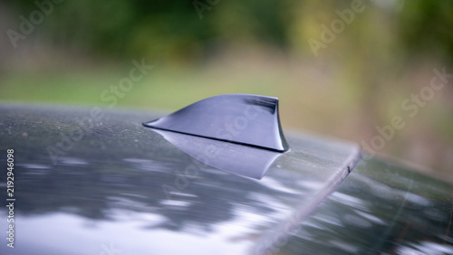 Car antenna on a vehicle parked in a natural setting near greenery