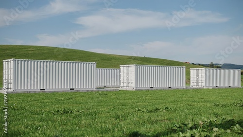 Row of white shipping storage containers installed on green meadow field with container shipping logistics