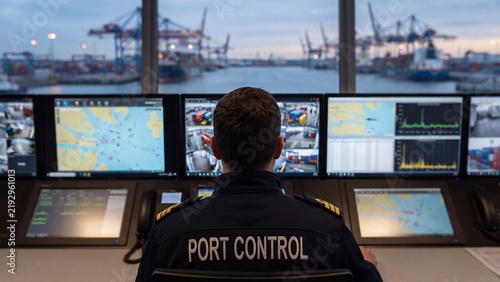 Port control officer monitoring shipping traffic screens for maritime logistics and harbor security operations