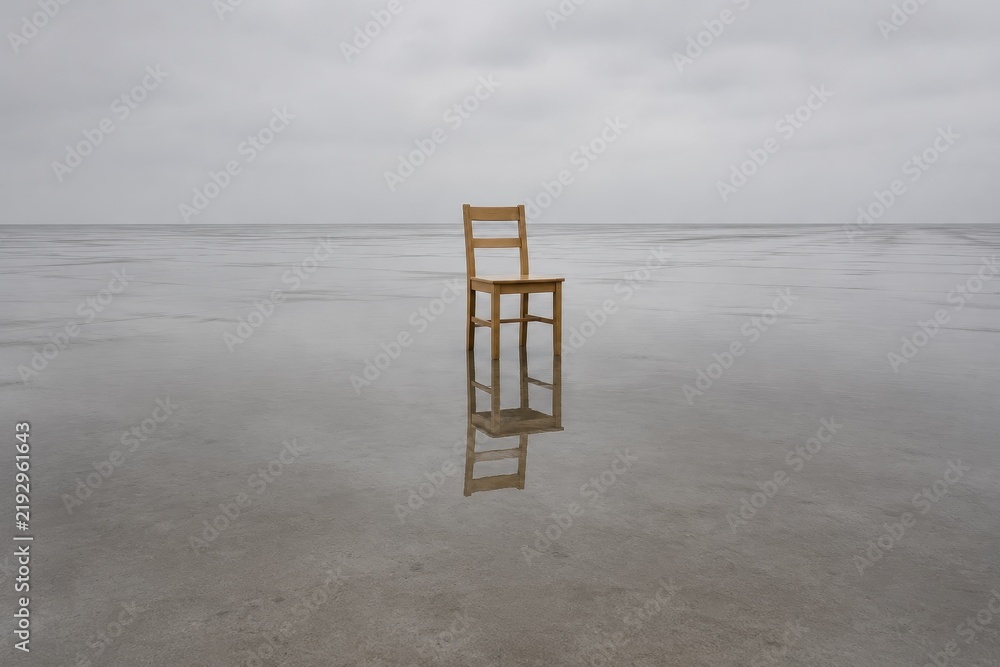 Obraz premium Single wooden chair standing in a wide shallow sheet of rainwater
