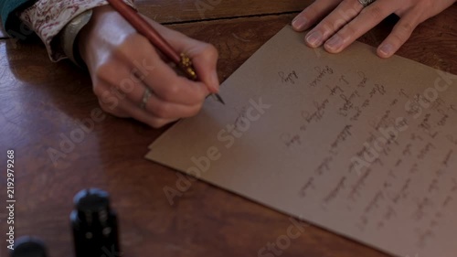 The girl holds a pen with ink and signs the document. She writes the letter in handwritten font. signing the document. 
