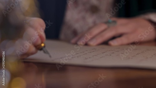 An antique young woman in a resurgent dress, sitting at the table and writing a letter with a vintage pen on an old paper sheet of parchment. The girl is writing a letter in handwritten script. 
