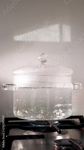 Boiling water in a transparent glass pot on a gas stove