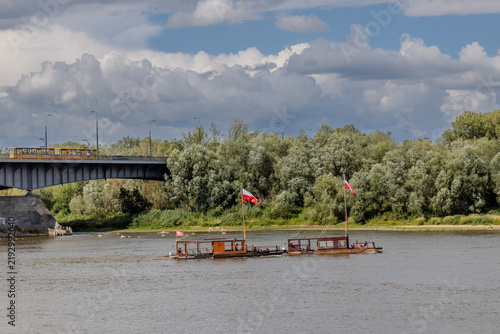 Fotografie Traditional wooden boats navigate the Vistula River in Warsaw, Poland, passing n