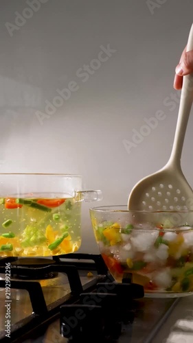 Lifting blanched vegetables from a glass pot with a slotted spoon