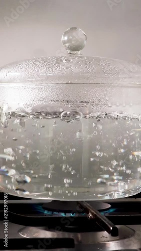 Boiling water in a transparent glass pot on a gas stove