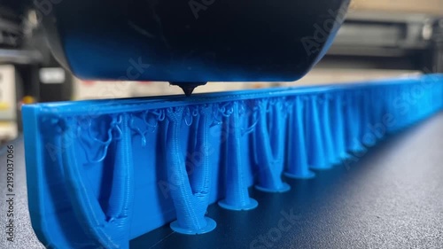 Close-Up of 3D Printer Building Long Blue Prototype with Supports