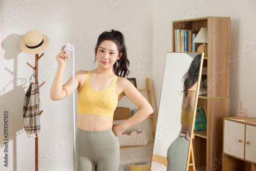 Принти на полотні Happy woman measuring waist with tape in sportswear at home