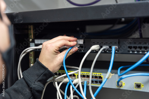 Cuadro en lienzo IT technician hand plugging ethernet network cable into server rack patch panel